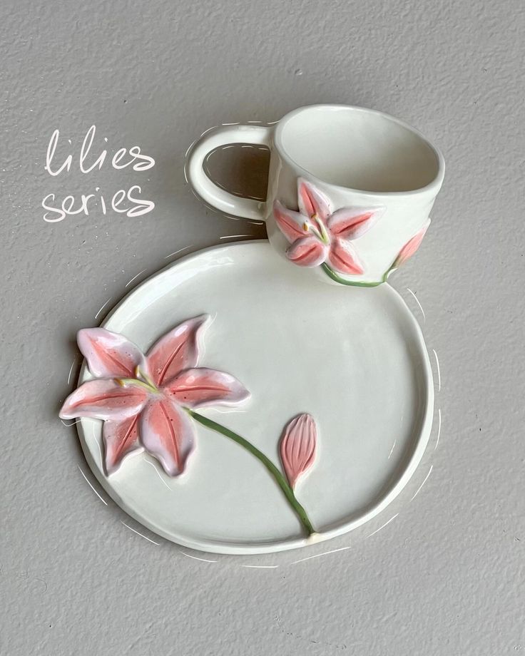 a cup and saucer with pink flowers painted on the side sitting on a plate