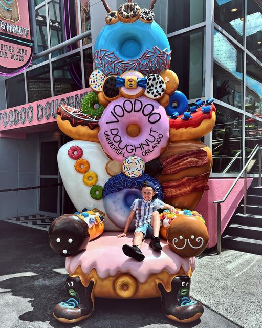 a giant doughnut sitting on top of a chair in front of a donut shop