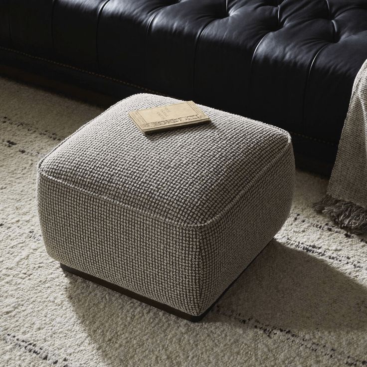 a small ottoman sitting on top of a white rug