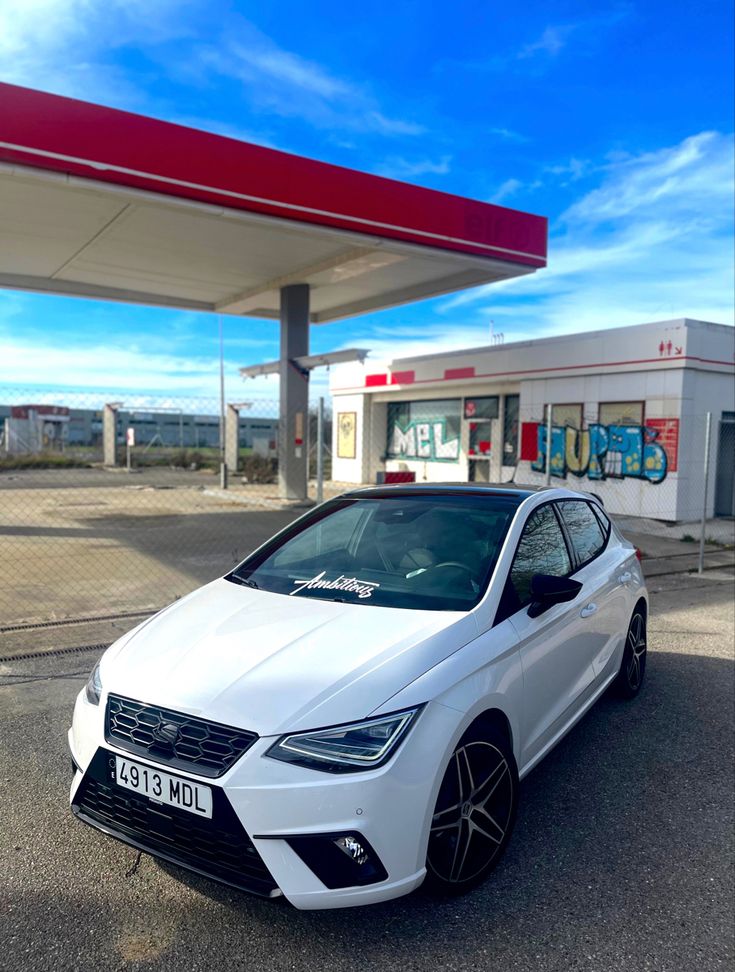 a white car parked in front of a gas station