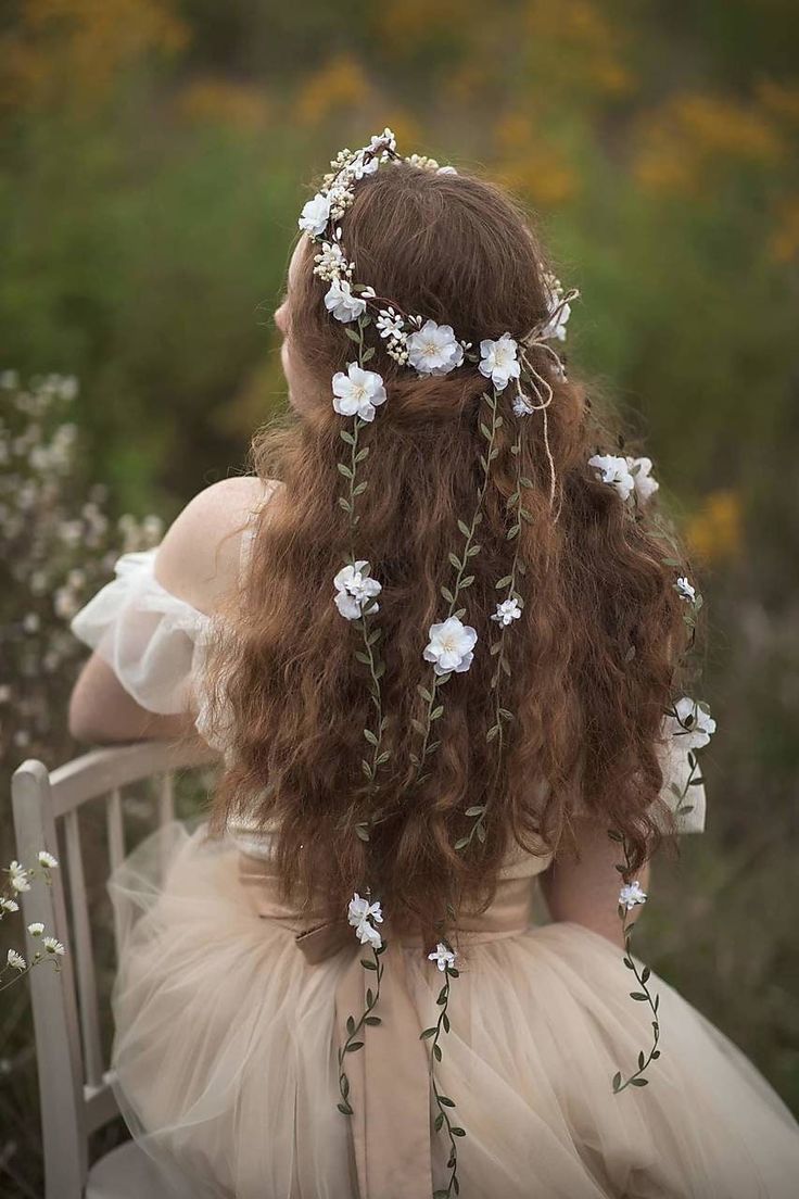 a woman with long hair sitting on a chair wearing a dress and flowers in her hair