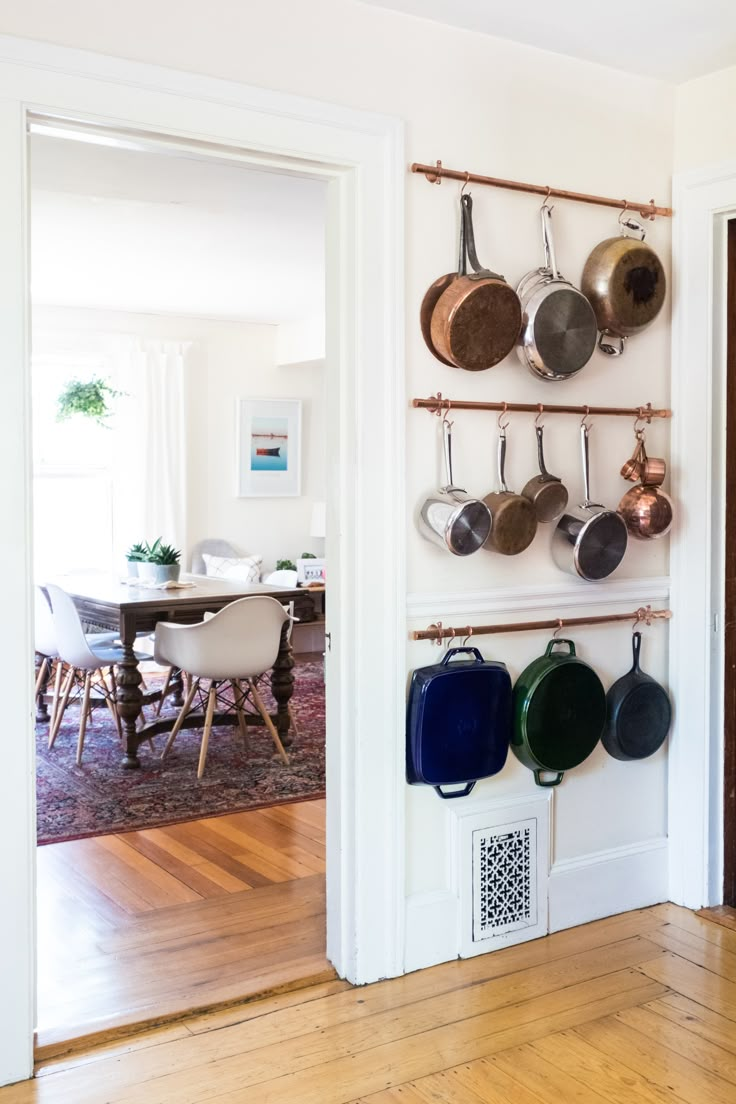 pots and pans are hanging on the wall in front of a dining room table