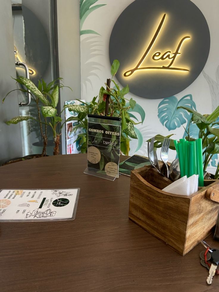 a wooden desk topped with plants next to a sign that says leaf on the wall