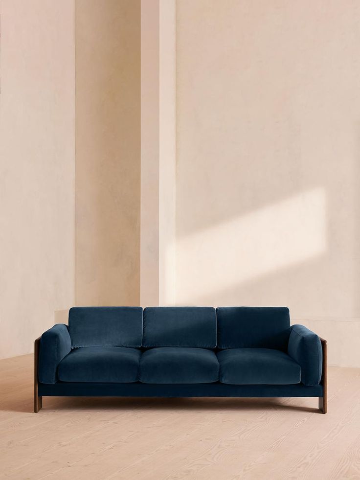 a blue couch sitting on top of a hard wood floor next to a white wall