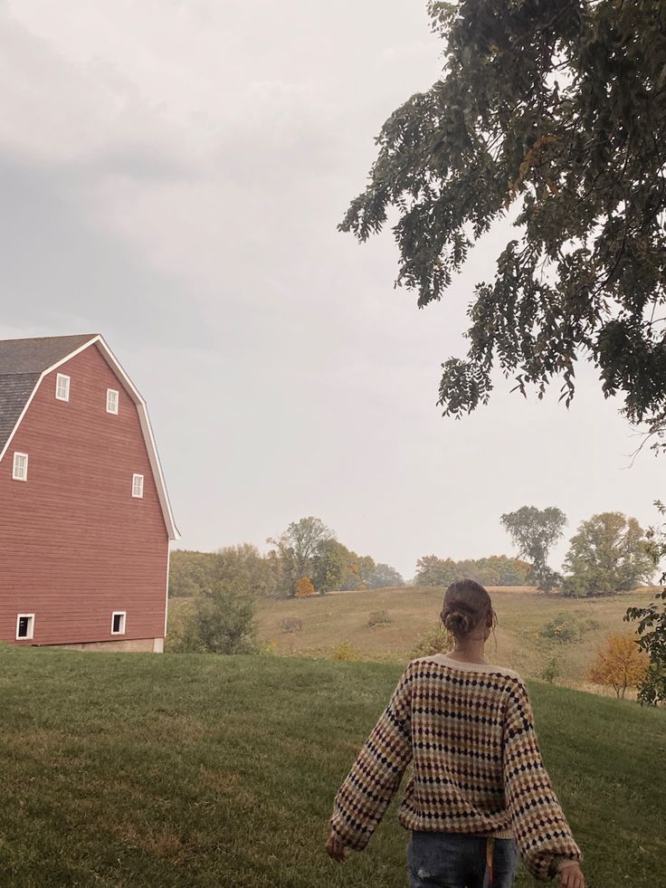 a person walking in front of a red barn