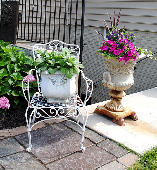 a white chair sitting next to a potted plant on top of a stone floor