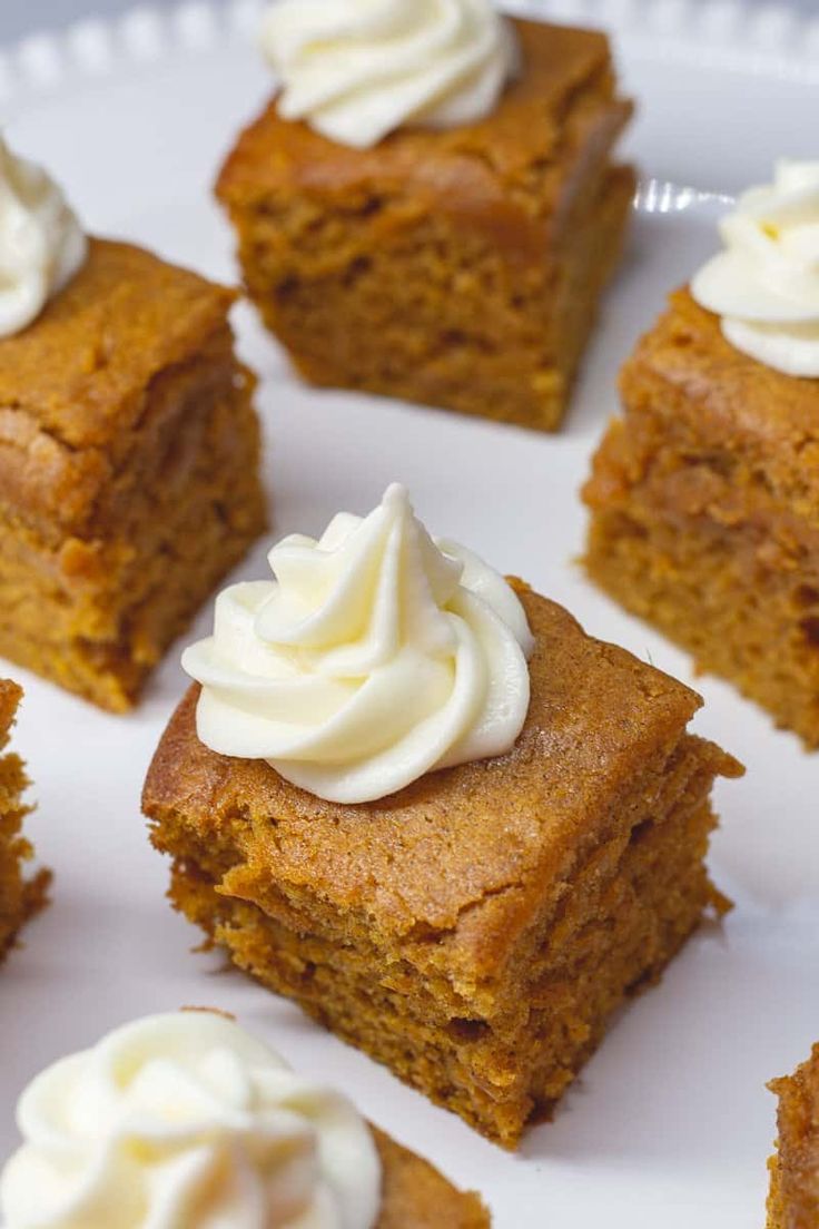 several pieces of pumpkin cake on a white plate with whipped cream frosting in the middle