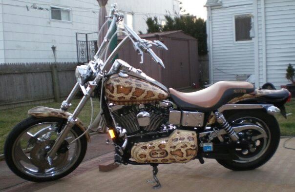 a motorcycle parked in front of a house on a driveway with no one around it