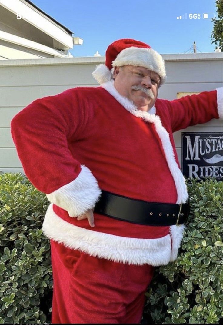 an older man dressed as santa clause pointing to the right with his hand on his hip