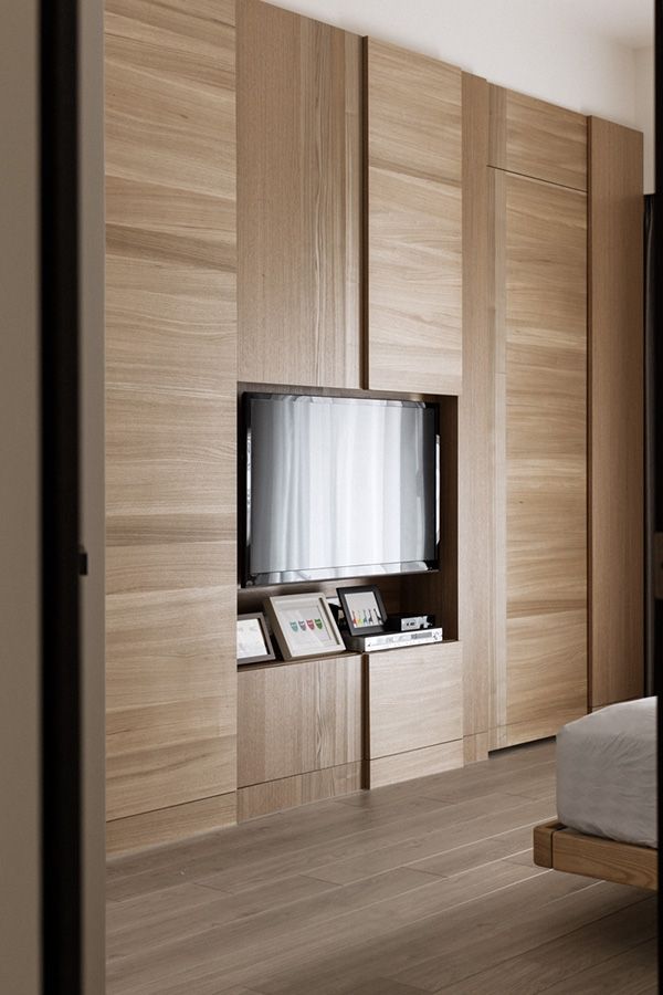 a bedroom with wooden cabinets and a flat screen tv mounted to the side of it