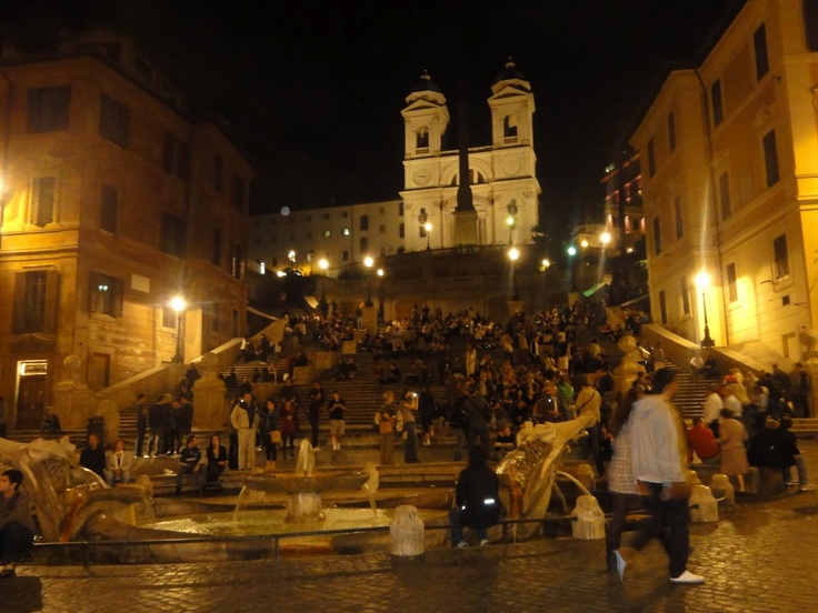 many people are walking up and down the steps in front of an old church at night