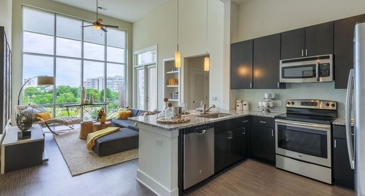 a kitchen with stainless steel appliances and lots of windows overlooking the trees in the distance