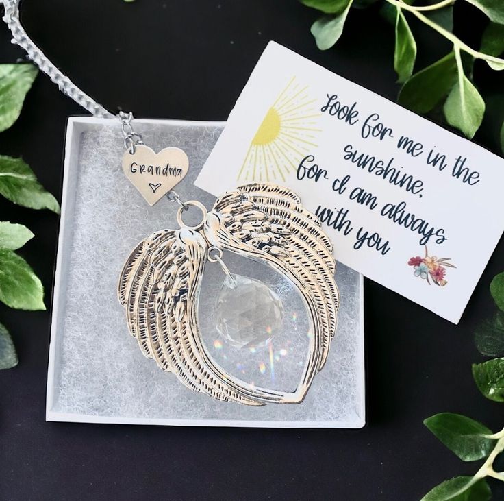 a necklace with a card attached to it sitting on top of a table next to some leaves