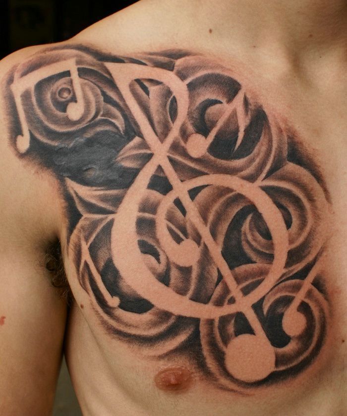 a tattoo with music notes and trebles on the side of his back shoulder