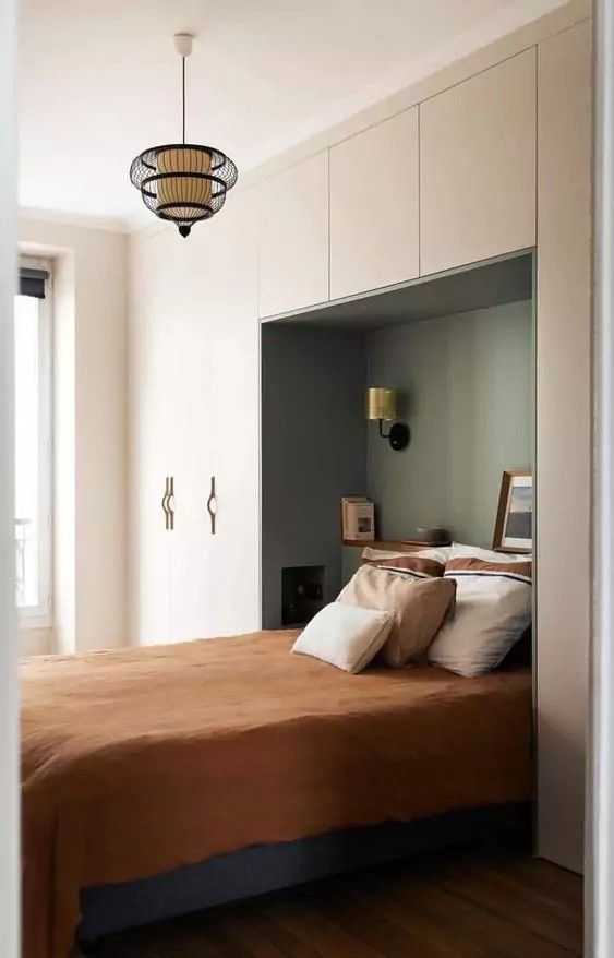 a bed sitting in a bedroom next to a window with a light hanging above it