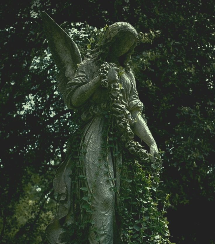 an angel statue with vines around it's body