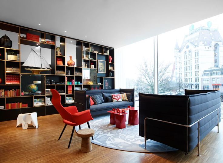 a living room filled with furniture and bookshelves next to a large glass window