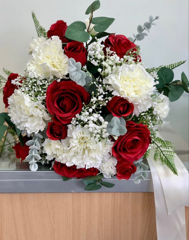 a bouquet of red and white flowers with greenery