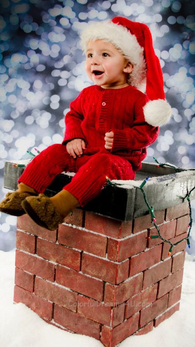 a baby sitting on top of a brick chimney wearing a santa hat