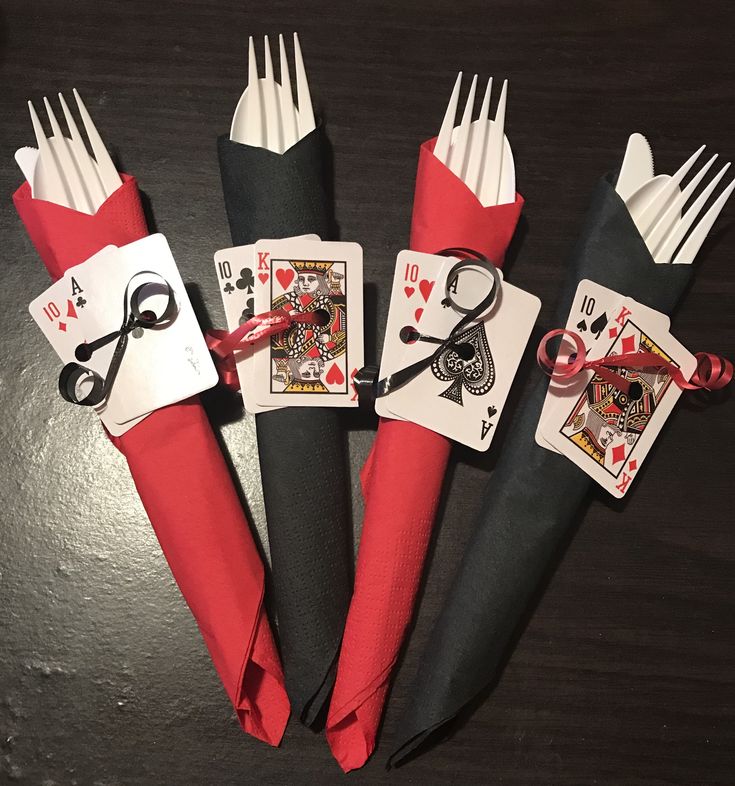 four forks with playing cards and scissors on them sitting next to each other in the middle of a table