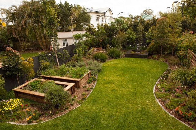 a garden with lots of plants and benches in the middle, surrounded by greenery