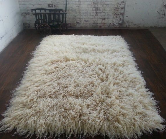 a white shaggy rug sitting on top of a wooden floor next to a brick wall