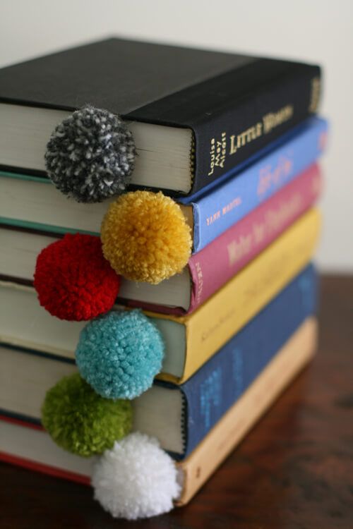 four books stacked on top of each other with pom - poms