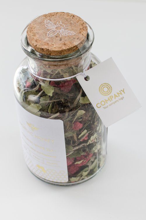 a glass jar filled with lots of green and red flowers next to a white tag