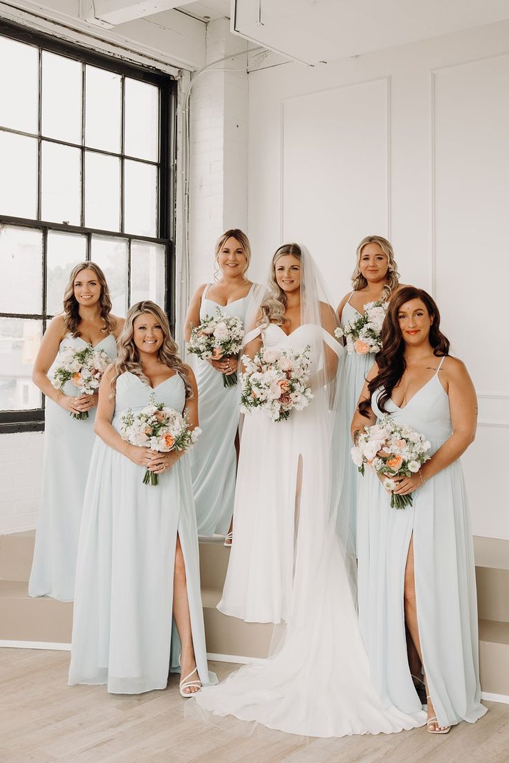 a group of bridesmaids pose for a photo in front of a large window