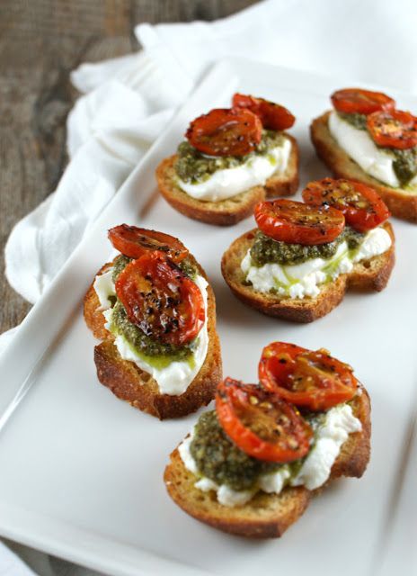 small appetizers with tomatoes and cream cheese are on a white plate next to a fork