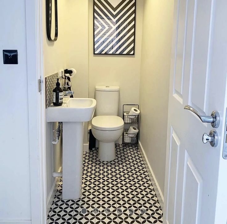 a white toilet sitting next to a sink in a bathroom under a painting on the wall