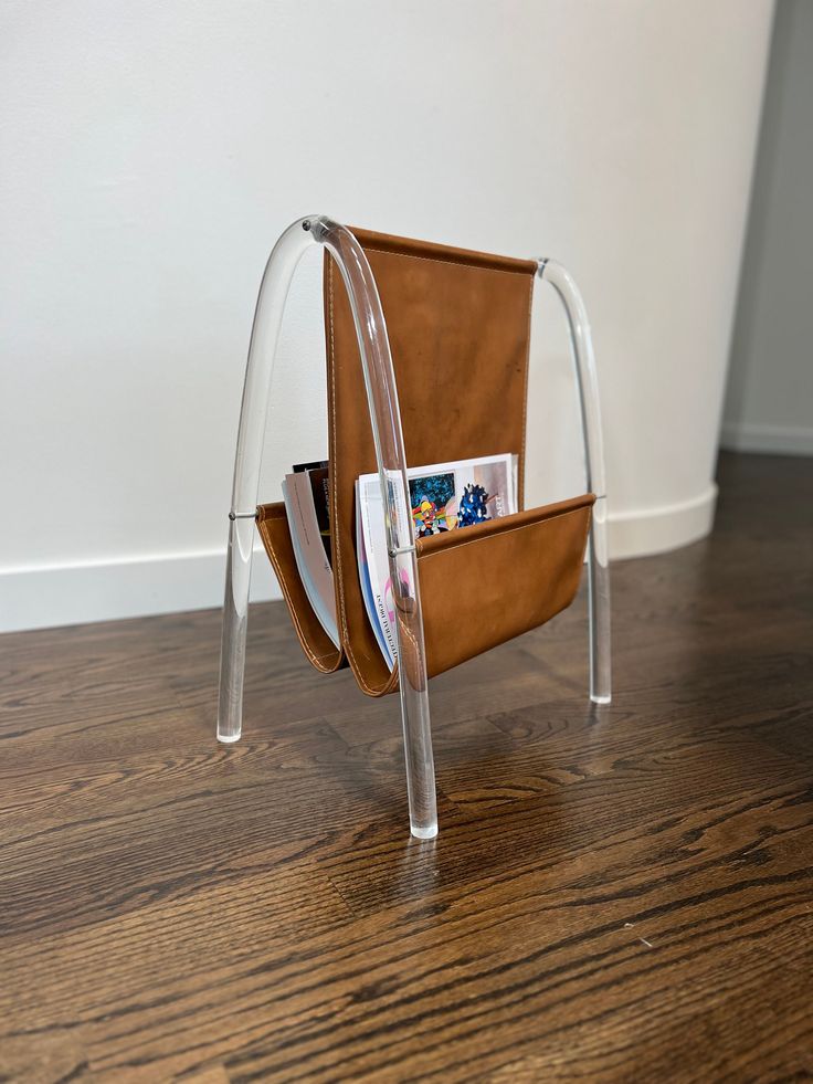 a magazine rack with magazines in it sitting on a wooden floor next to a white wall