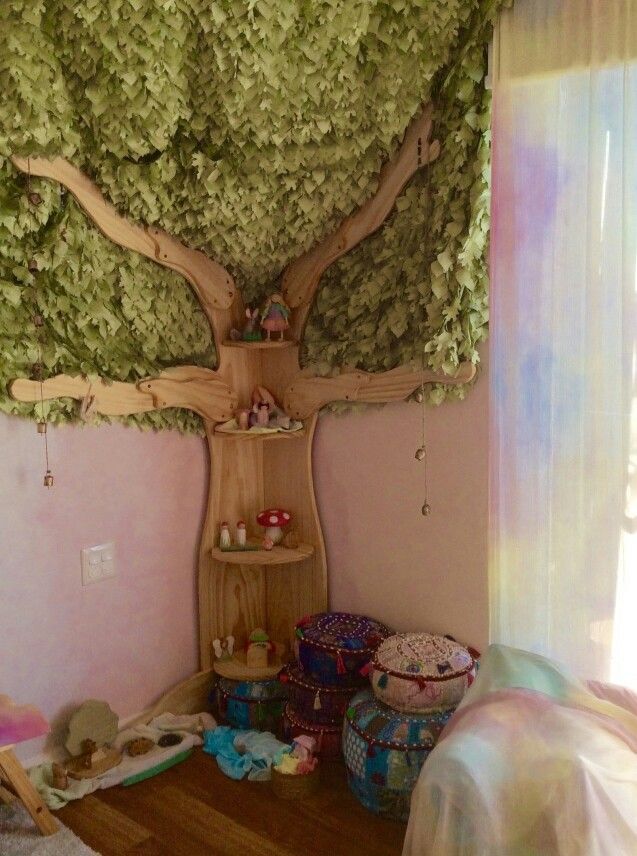 a room with a tree on the wall and other items scattered about in front of it