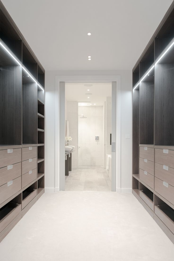 an empty walk in closet with drawers and lights on the walls, along with white carpeting