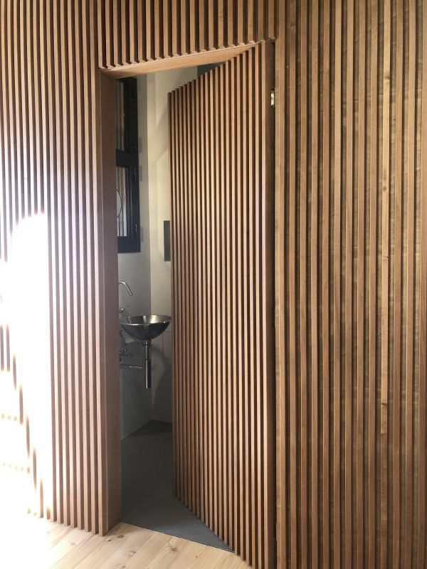 an open door leading into a bathroom with wood slats on the walls and floor