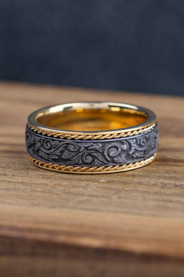 two gold and silver wedding bands sitting on top of a wooden table