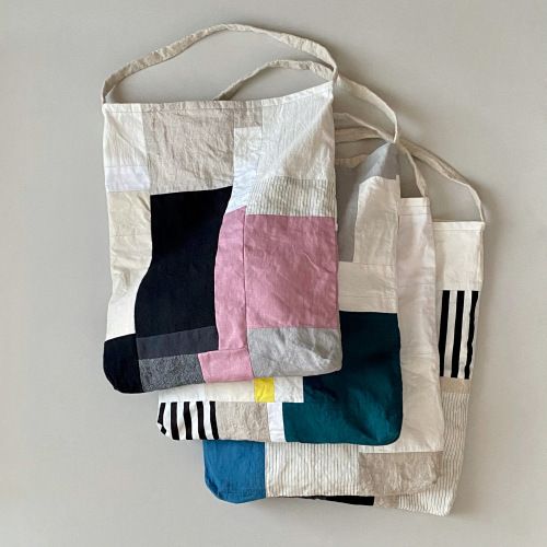 a white bag with multicolored patchwork on the front and side, hanging from a wall