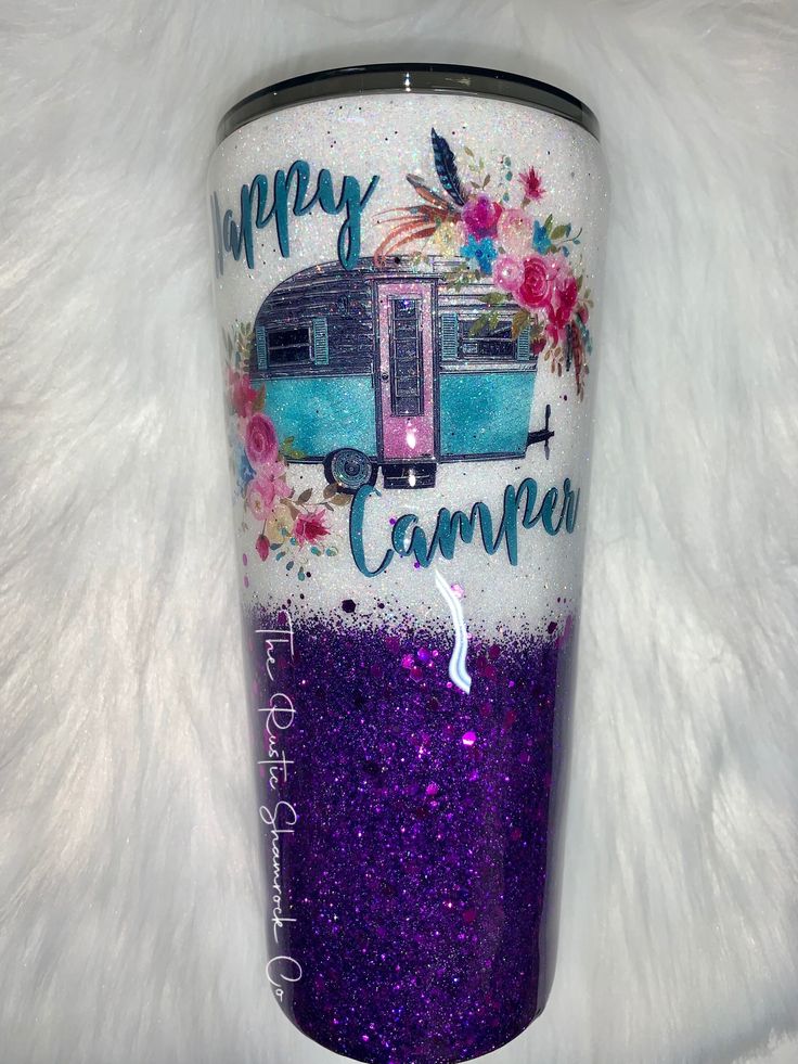 a purple and blue tumbler with the words happy camper painted on it's side