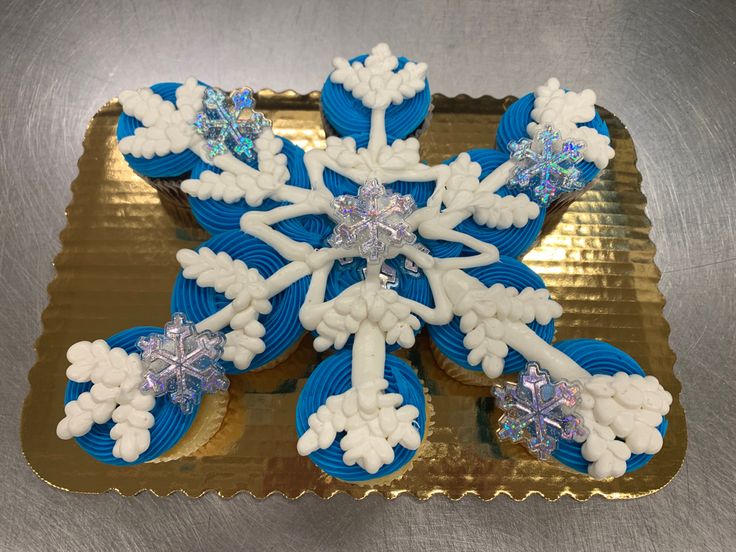 cupcakes decorated with icing and snowflakes are on a gold platter