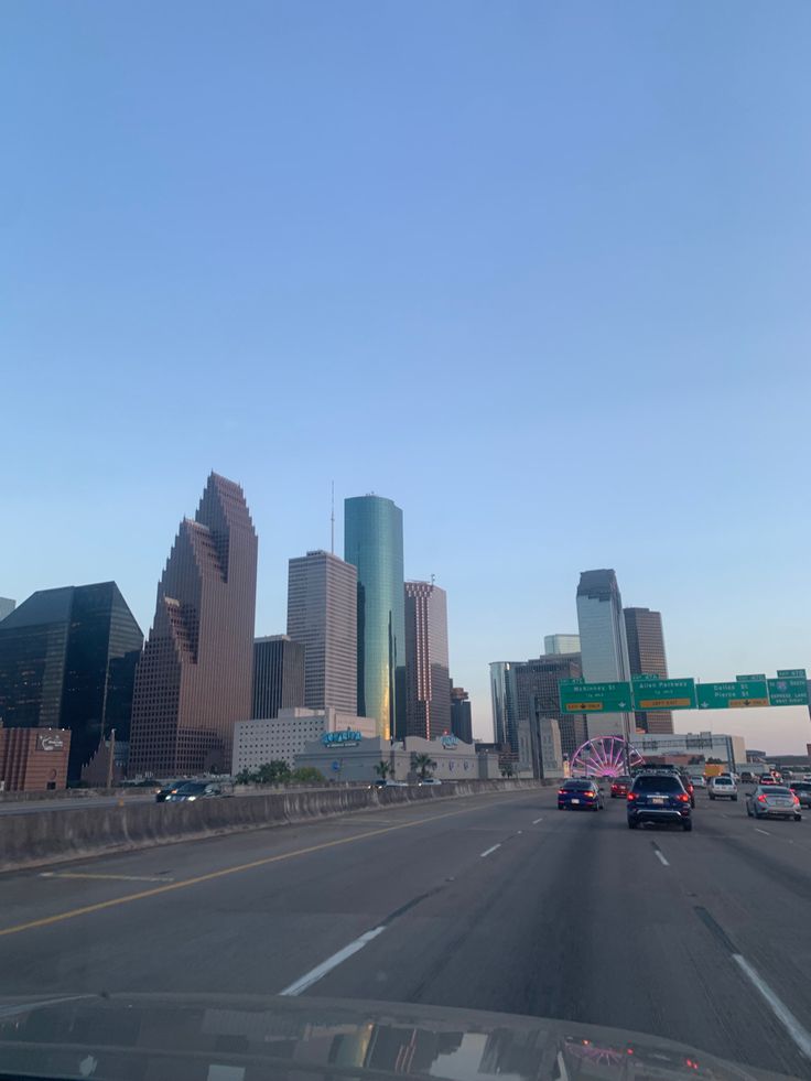 cars driving down the highway in front of tall buildings