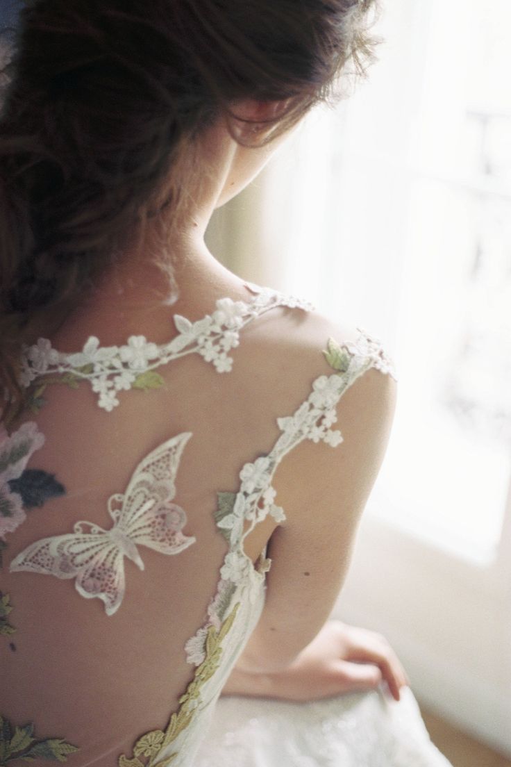 the back of a woman's wedding dress with butterflies on it