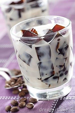 two glasses filled with ice cream and topped with coffee beans on a purple tablecloth