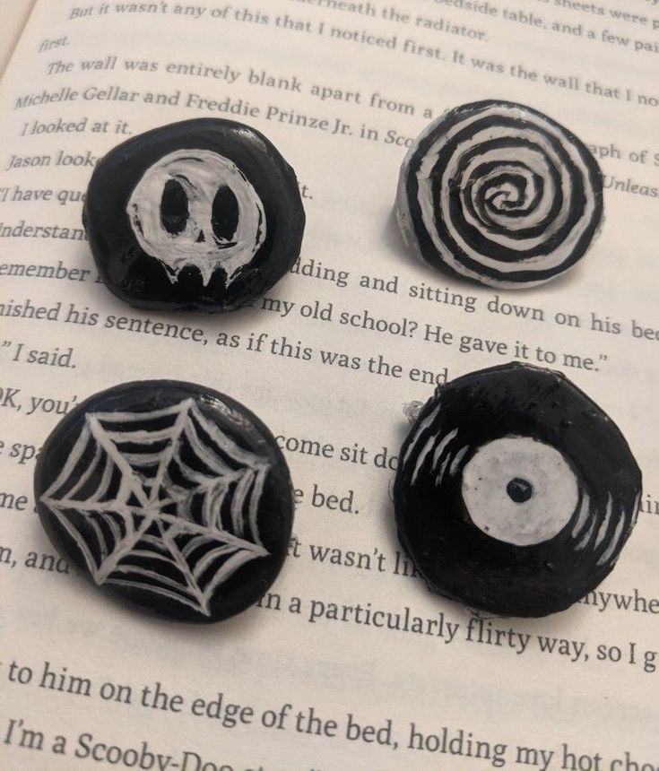 three black and white buttons on top of an open book with spider webs in the middle