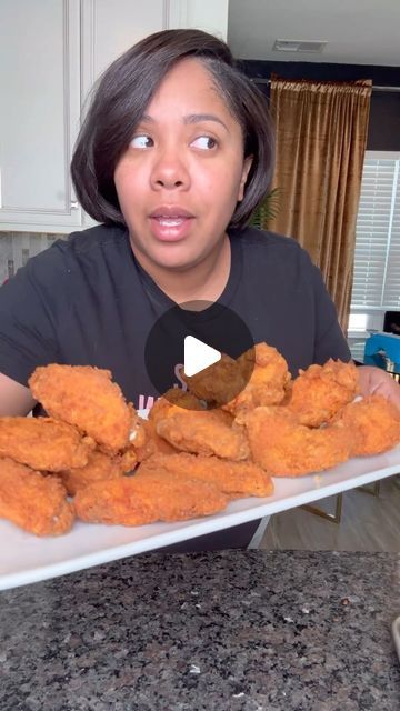 a woman is holding a platter full of fried chicken