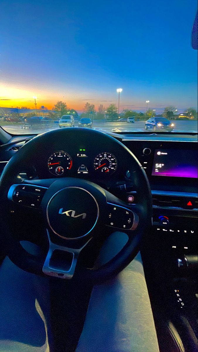 the interior of a car with dashboard lights and gauges at sunset or sunrise time