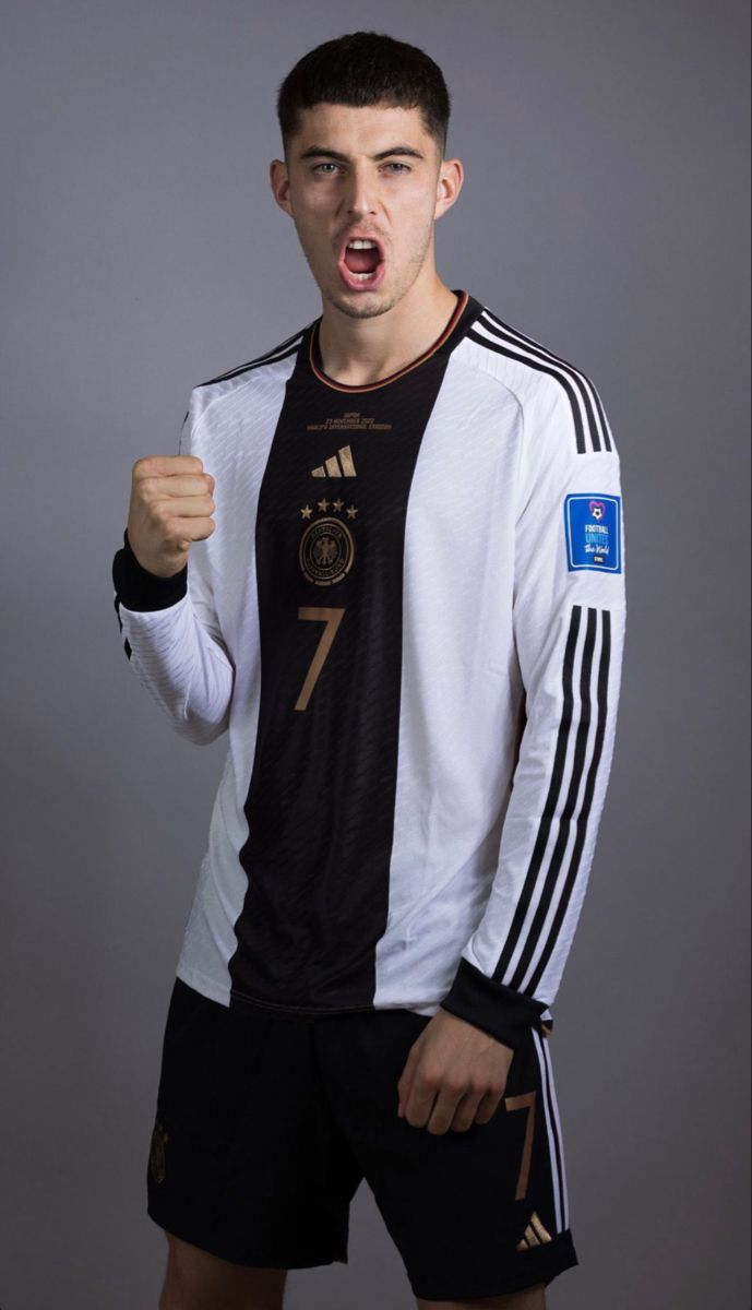 a young man in black and white soccer uniform holding his fist up to the camera