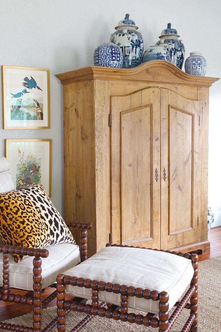 a living room scene with focus on the armoire and footstool in the foreground