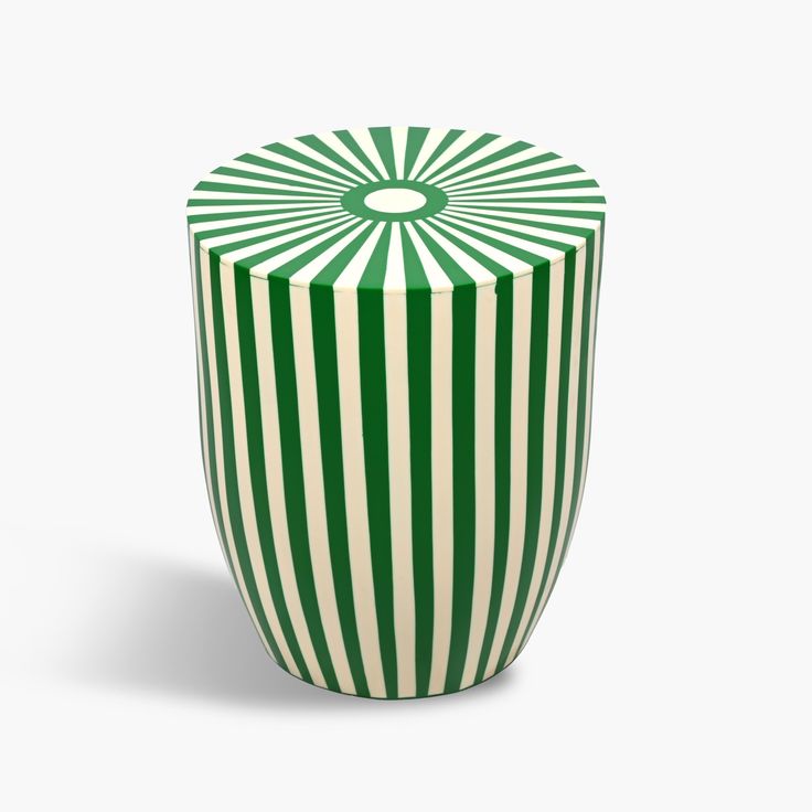 a green and white striped vase sitting on top of a table in front of a white background