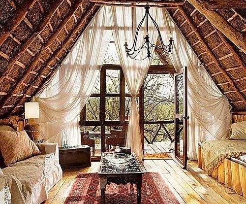 a living room filled with furniture and a large window next to a wooden floor covered in curtains