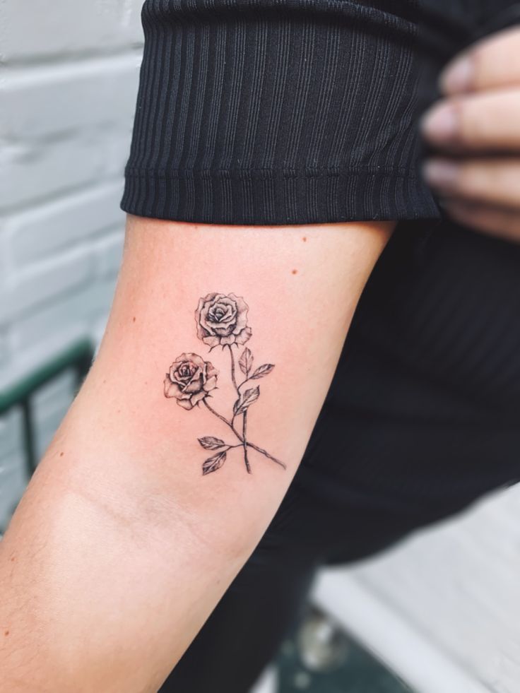 a person with a tattoo on their arm holding a flower in one hand and a rose in the other